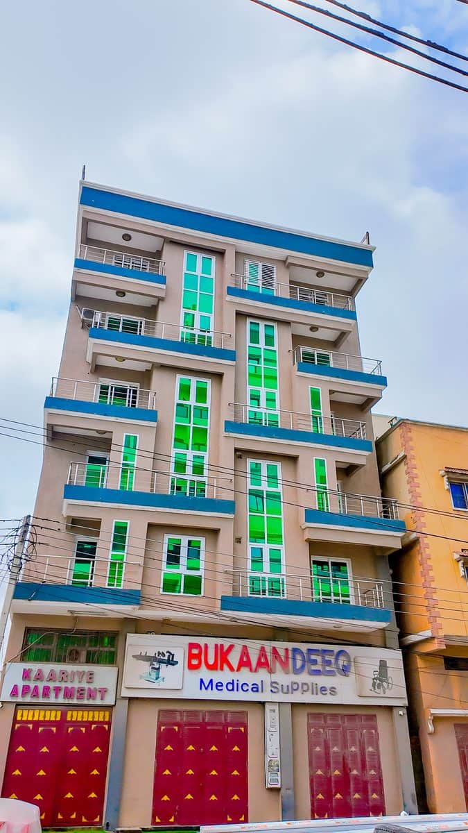 The Kaariye Apartments building in Mogadishu, its balconies and green-glazed windows rising above the shops and traffic on the street below