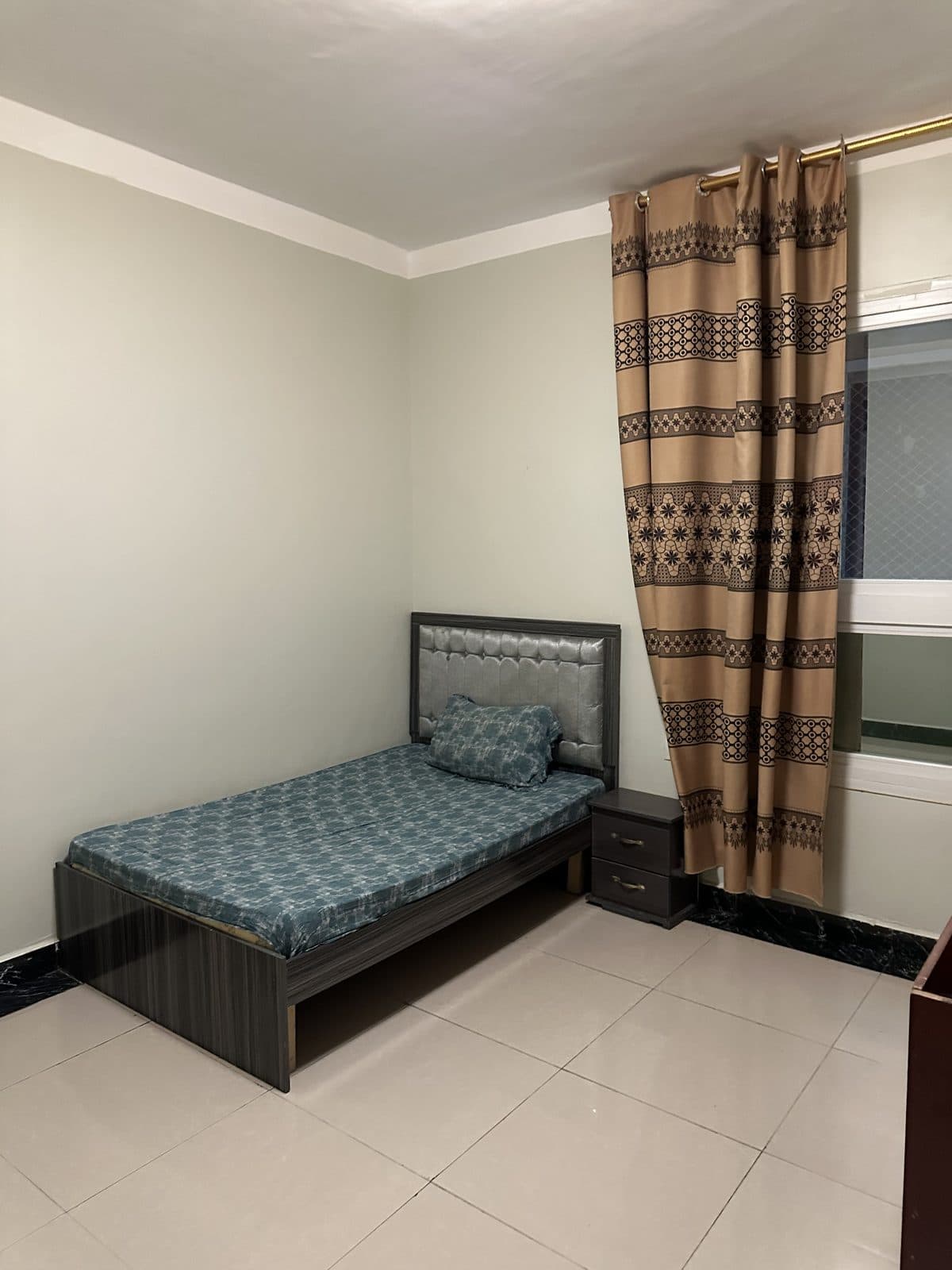 Second bedroom with a single bed, a grey buttoned headboard, a small bedside cabinet and patterned curtains