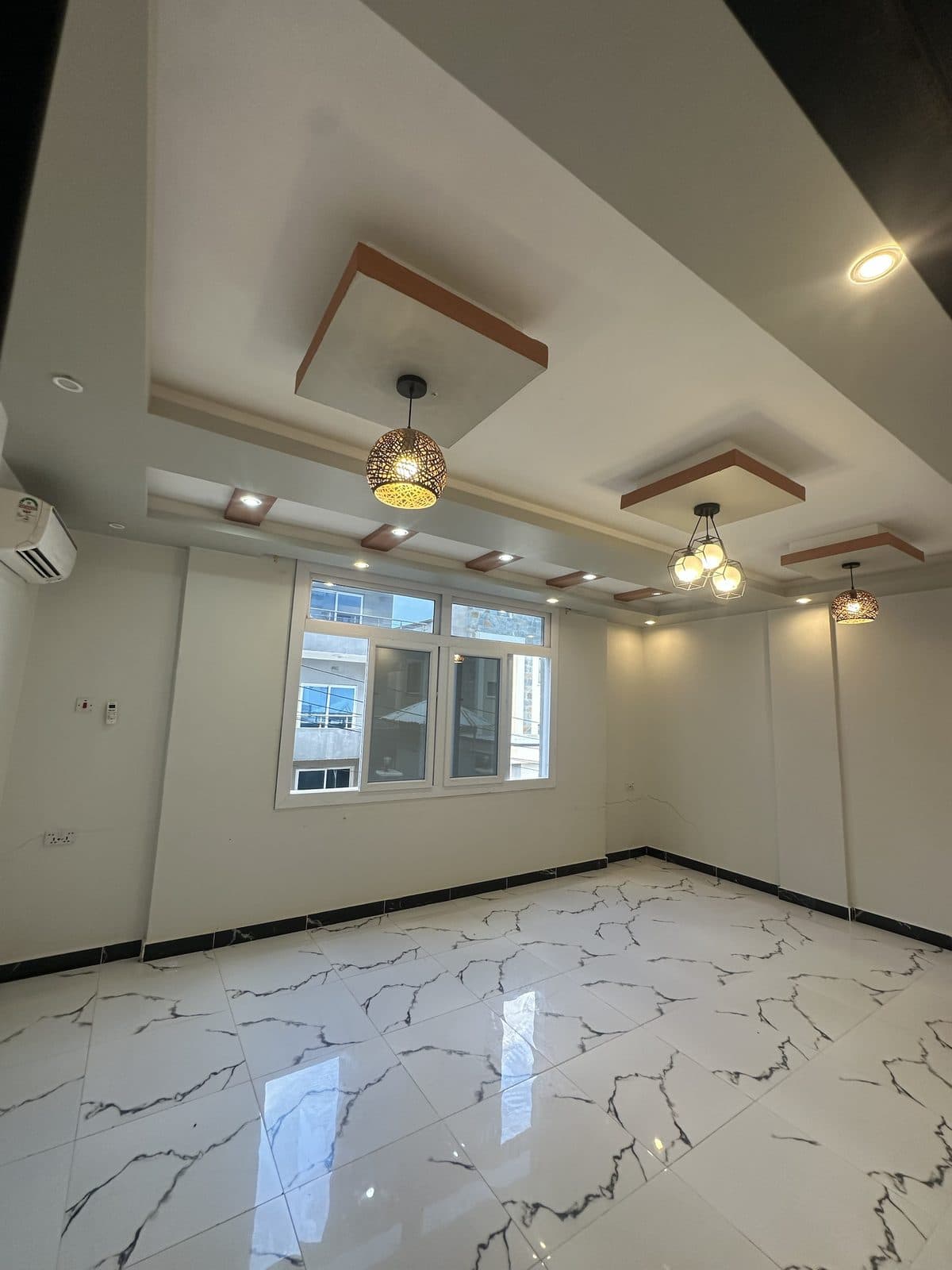 Unfurnished living room with a coffered feature ceiling, woven pendant lights and spotlights, a wall-mounted air conditioner and a wide window