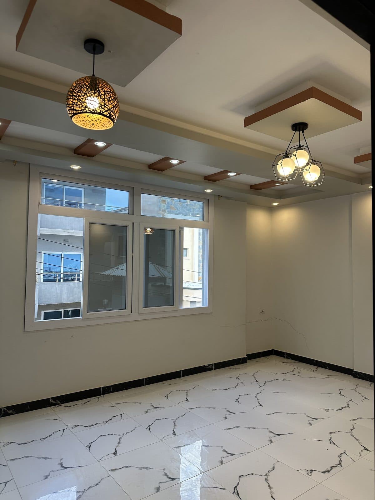 Reception room with a woven pendant lamp, a geometric three-bulb pendant, recessed spotlights and tall sliding windows
